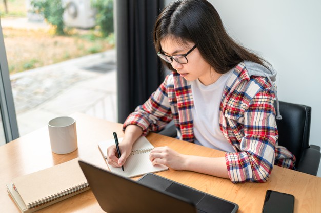 Jovem asiática estudando frente a computador